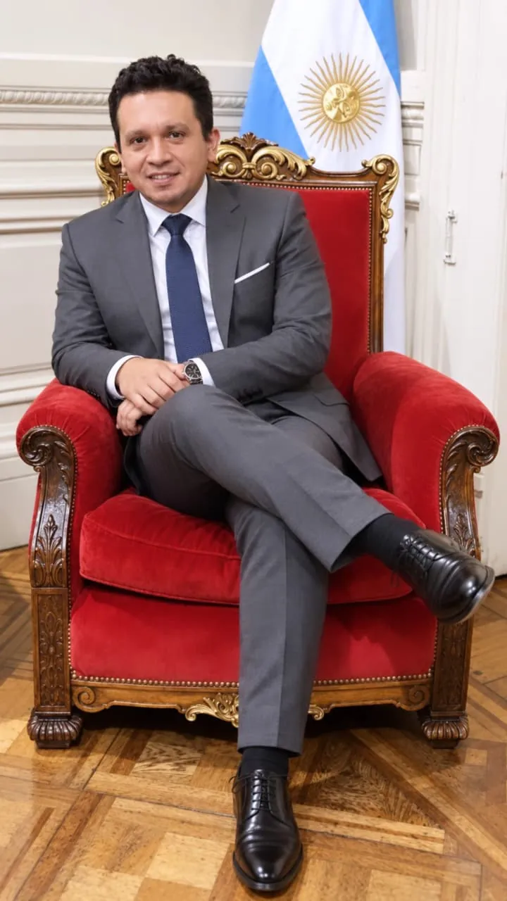 Diego Macana Roa seated in a red armchair next to the Argentine flag